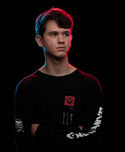 Een jonge esports-speler in een zwart Sentinels-tenue tegen een donkere achtergrond met neonlicht